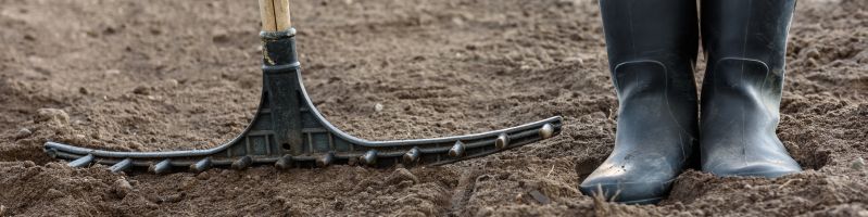 Un jardinier ameublit sa terre avec un rateau
